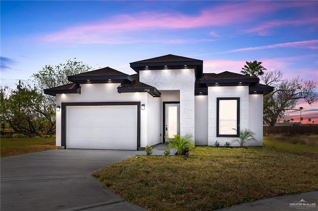 view of front of property featuring a front yard, concrete driveway, an attached garage, and stucco siding