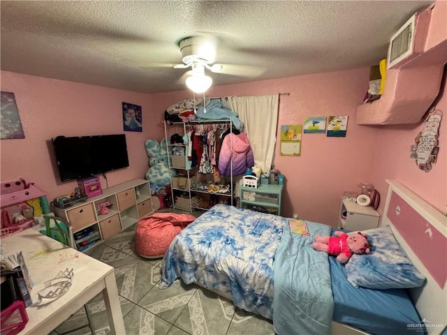 bedroom with ceiling fan, tile patterned flooring, and a textured ceiling