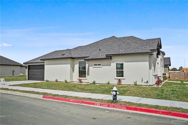 view of front facade featuring an attached garage, a shingled roof, concrete driveway, stucco siding, and a front lawn