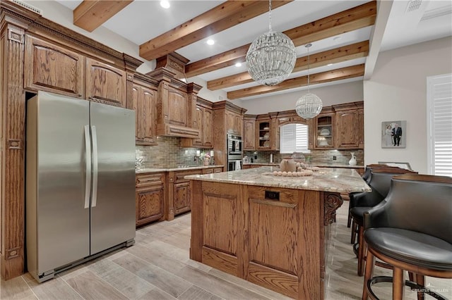 kitchen with beam ceiling, light stone countertops, stainless steel appliances, an inviting chandelier, and a kitchen island