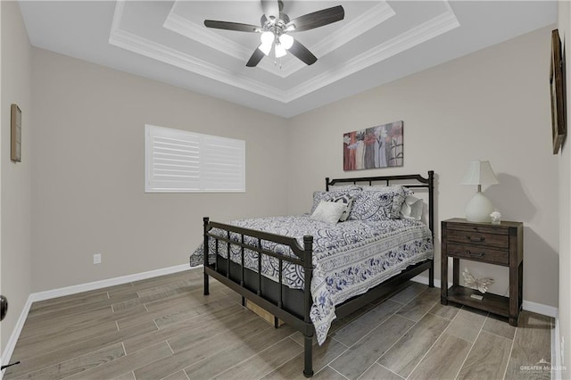 bedroom with hardwood / wood-style flooring, ceiling fan, and a tray ceiling