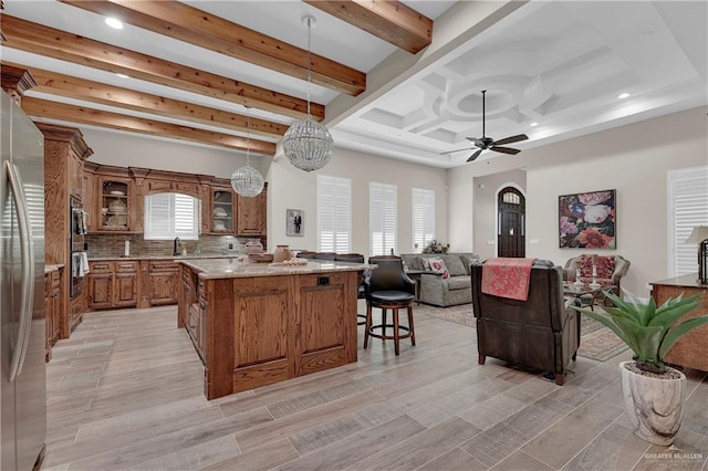 kitchen with pendant lighting, backsplash, light hardwood / wood-style flooring, a kitchen island, and stainless steel appliances