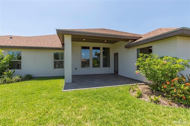 back of property featuring a patio area, a lawn, and stucco siding