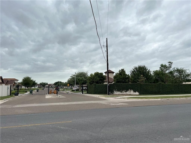 view of street featuring a gate, a gated entry, curbs, and sidewalks