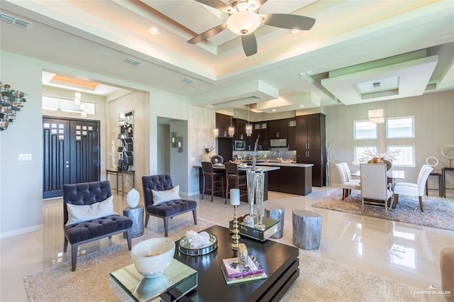 living area with a tray ceiling, visible vents, and baseboards