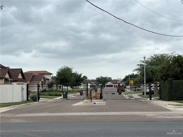 view of road with street lighting, curbs, a gate, and sidewalks
