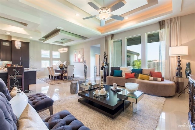 living area with baseboards, a ceiling fan, a tray ceiling, and recessed lighting