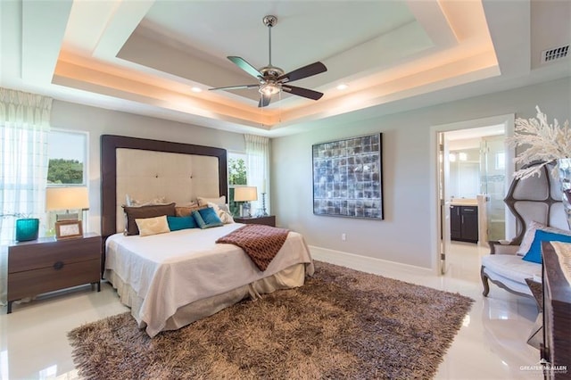 bedroom featuring visible vents, baseboards, ensuite bath, and a tray ceiling