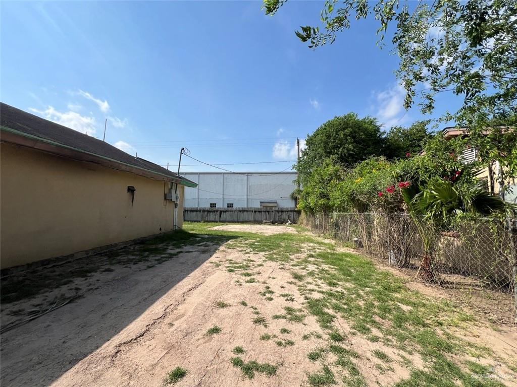 view of yard with dirt driveway and fence