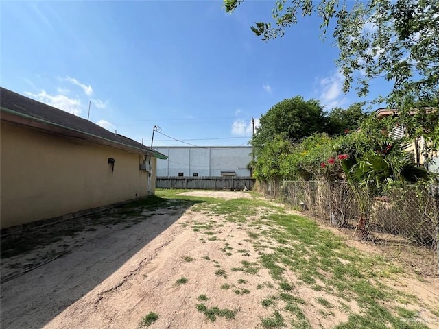 view of yard with dirt driveway and fence