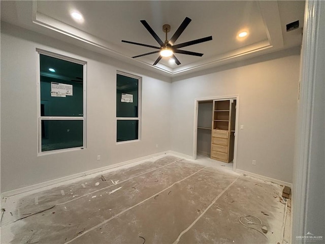 unfurnished bedroom featuring a walk in closet, a raised ceiling, and ceiling fan