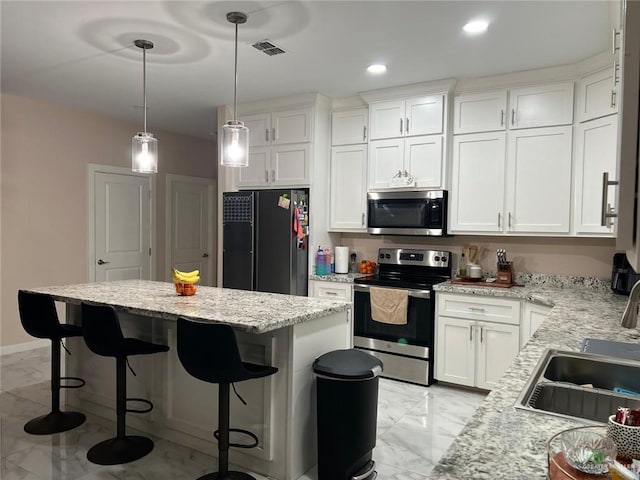 2429 Summer Breeze St, Mission, TX 78574 - kitchen featuring appliances with stainless steel finishes, a center island, marble finish floor, and white cabinetry