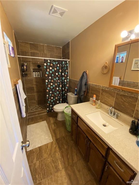 bathroom featuring a shower with shower curtain, vanity, and toilet