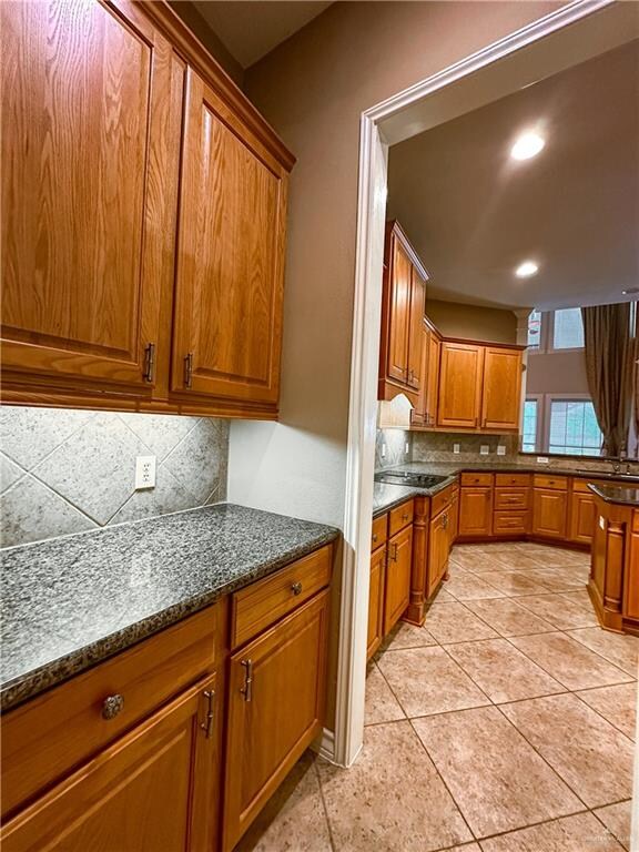 kitchen featuring backsplash, dark stone countertops, and light tile patterned floors