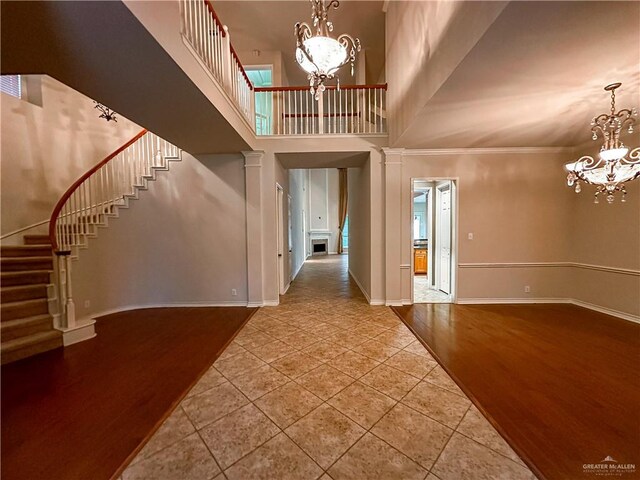 entrance foyer featuring hardwood / wood-style flooring, crown molding, a high ceiling, and an inviting chandelier