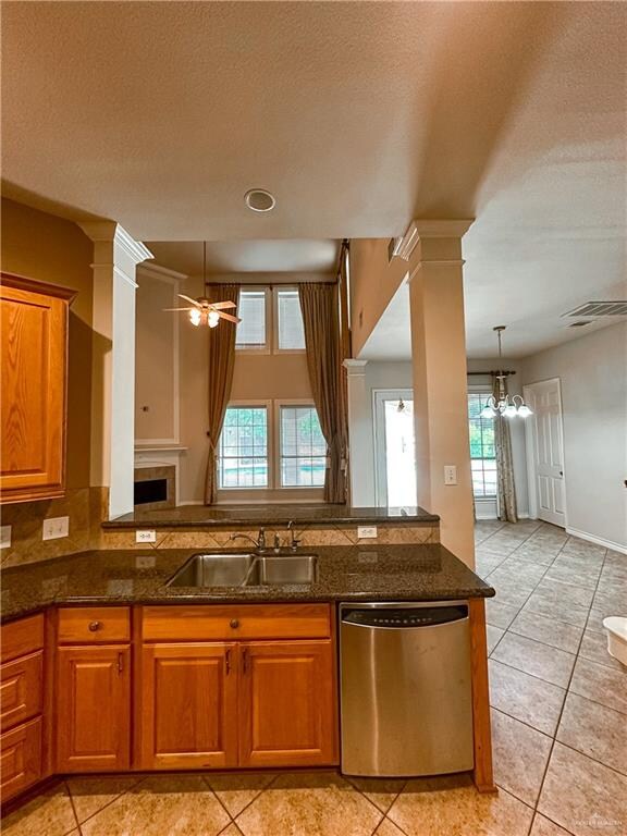 kitchen featuring a textured ceiling, stainless steel dishwasher, plenty of natural light, and sink