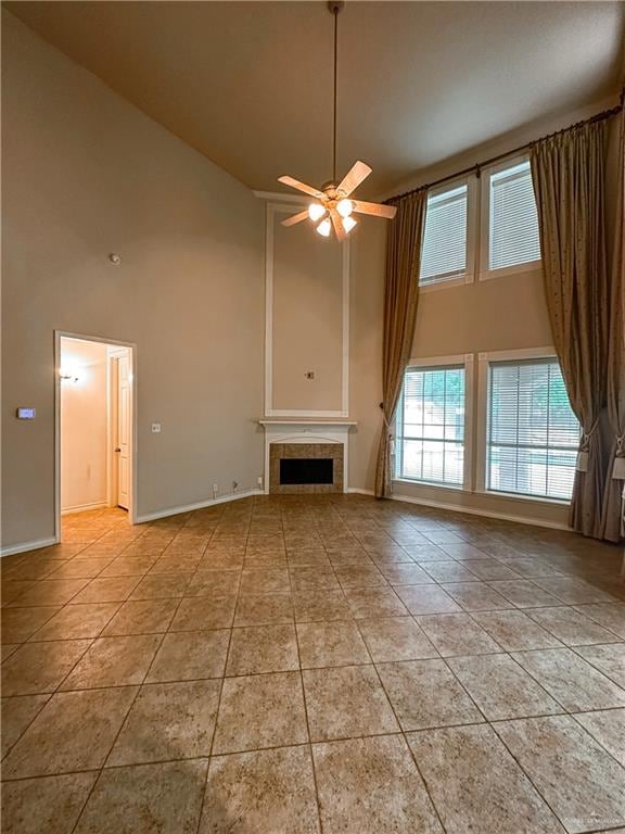 unfurnished living room with ceiling fan, light tile patterned floors, high vaulted ceiling, and a tiled fireplace