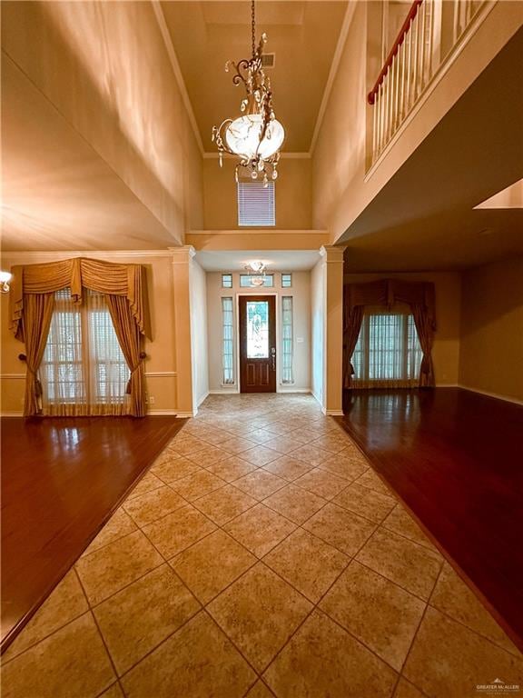 foyer entrance with a towering ceiling, wood-type flooring, and a notable chandelier