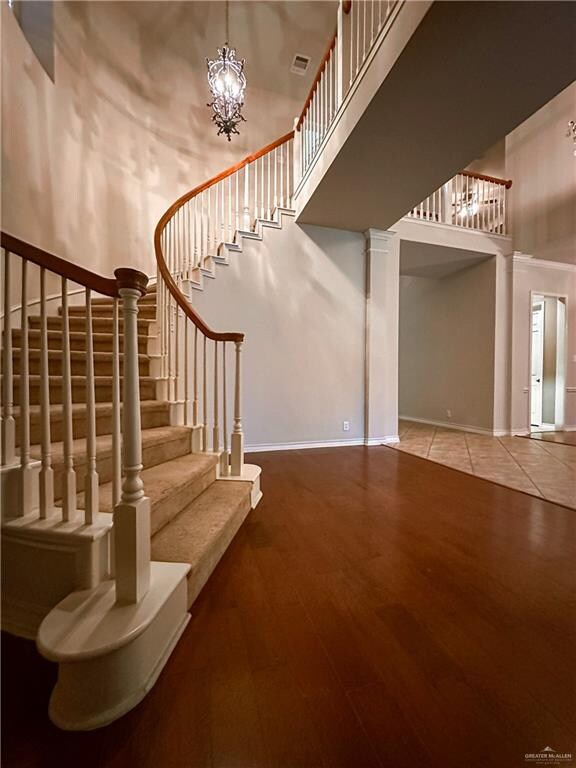 stairs featuring hardwood / wood-style flooring, a high ceiling, and a chandelier