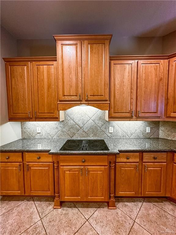 kitchen featuring tasteful backsplash, black electric stovetop, and light tile patterned floors