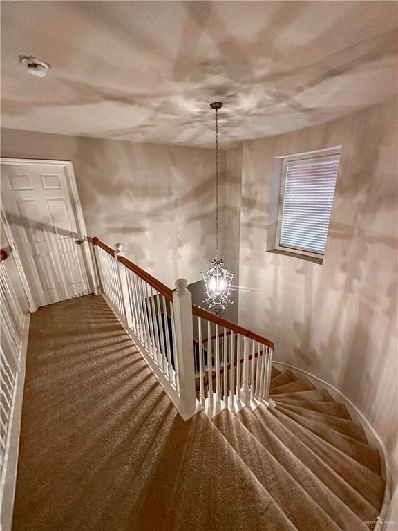 stairs with carpet flooring and a chandelier