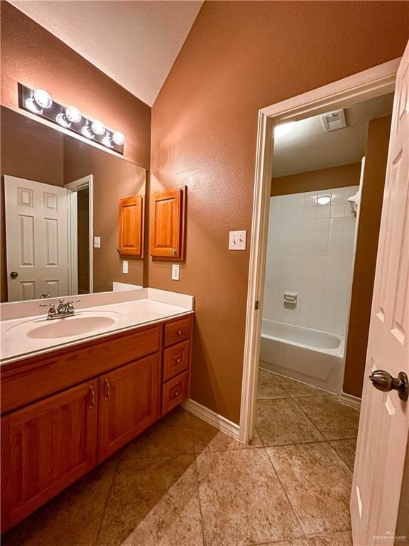 bathroom featuring tile patterned floors, vanity, lofted ceiling, and washtub / shower combination