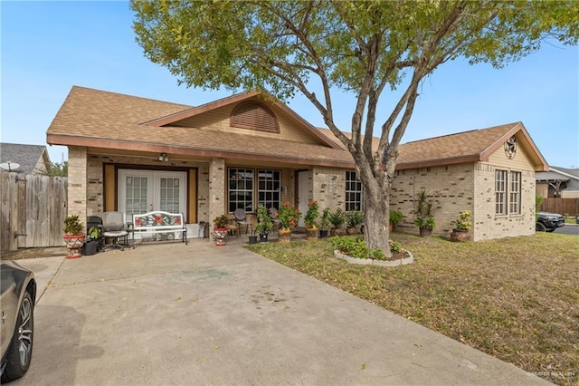 ranch-style house with a front yard, covered porch, and french doors