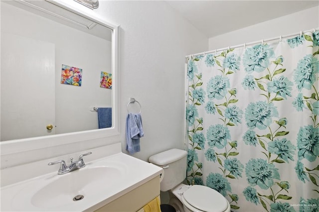 bathroom featuring toilet, vanity, and walk in shower