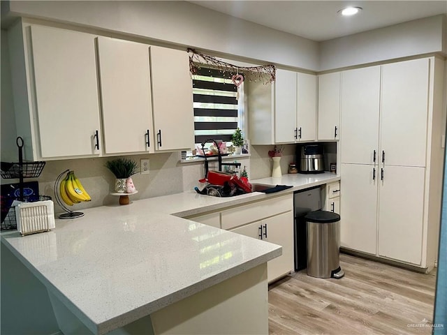 kitchen with white cabinets, light wood-type flooring, and kitchen peninsula