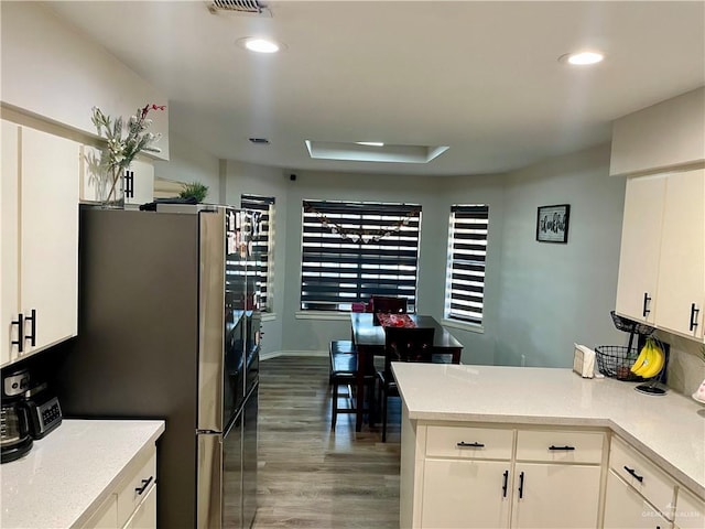 kitchen featuring white cabinetry, dark hardwood / wood-style floors, kitchen peninsula, and stainless steel refrigerator