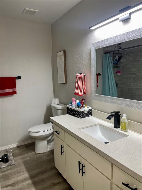 bathroom featuring hardwood / wood-style flooring, vanity, toilet, and a shower with curtain