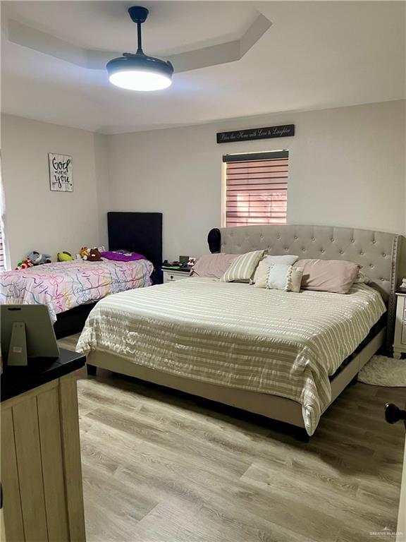 bedroom featuring a tray ceiling and light hardwood / wood-style floors