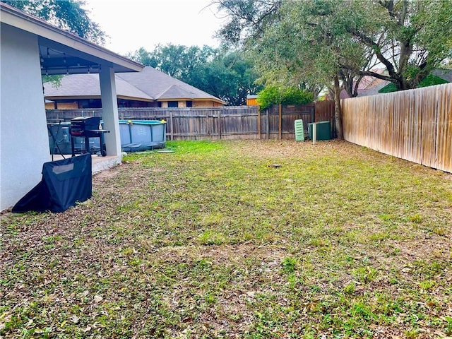 view of yard with a fenced in pool and central AC