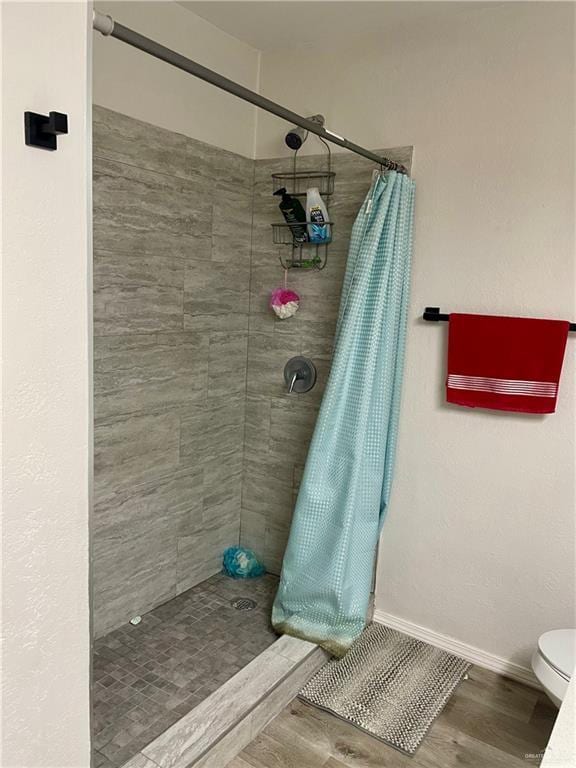 bathroom with wood-type flooring, toilet, and walk in shower