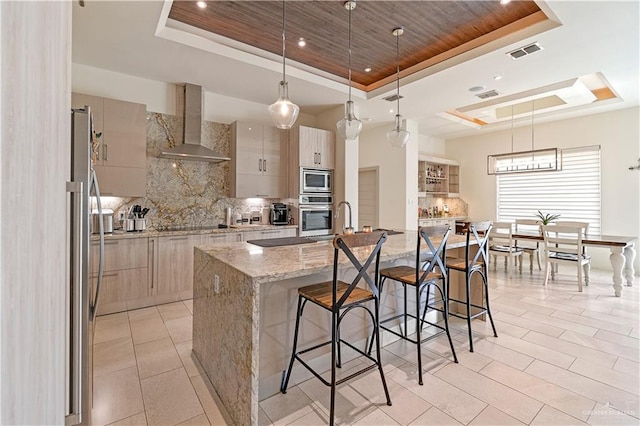2520 Colvin Ave, Edinburg, TX 78539 - kitchen with light stone countertops, appliances with stainless steel finishes, a raised ceiling, wall chimney range hood, and a large island