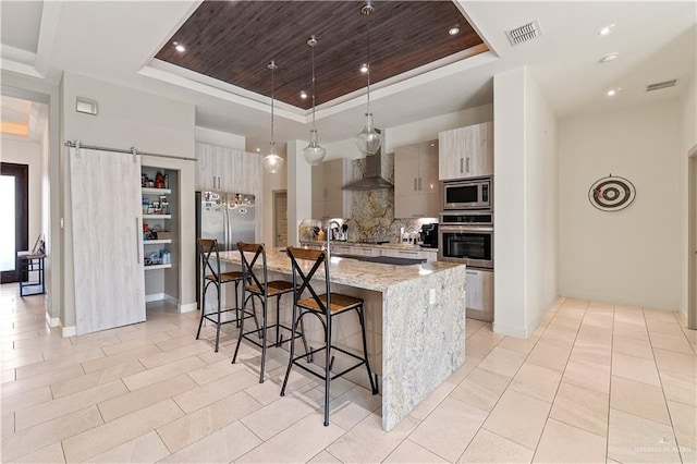 2520 Colvin Ave, Edinburg, TX 78539 - kitchen with a barn door, stainless steel appliances, a raised ceiling, and a kitchen island with sink