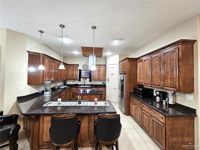 kitchen featuring hanging light fixtures, kitchen peninsula, a breakfast bar, light tile patterned flooring, and appliances with stainless steel finishes