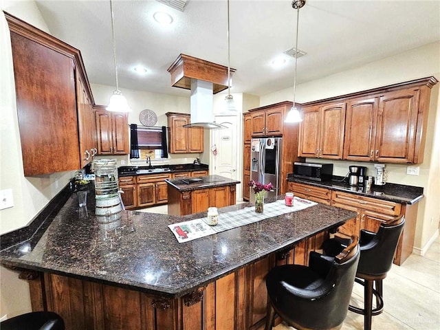 kitchen featuring a kitchen bar, stainless steel appliances, exhaust hood, decorative light fixtures, and a kitchen island