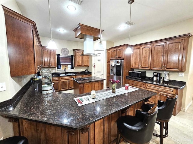 kitchen featuring appliances with stainless steel finishes, a center island, hanging light fixtures, a breakfast bar area, and range hood