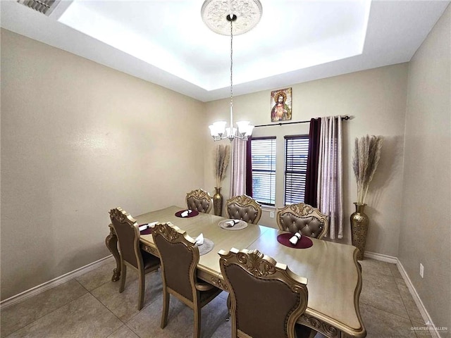 tiled dining space featuring a tray ceiling and an inviting chandelier