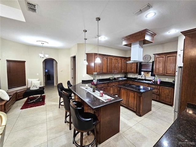 kitchen with pendant lighting, a center island, light tile patterned floors, island exhaust hood, and stainless steel refrigerator