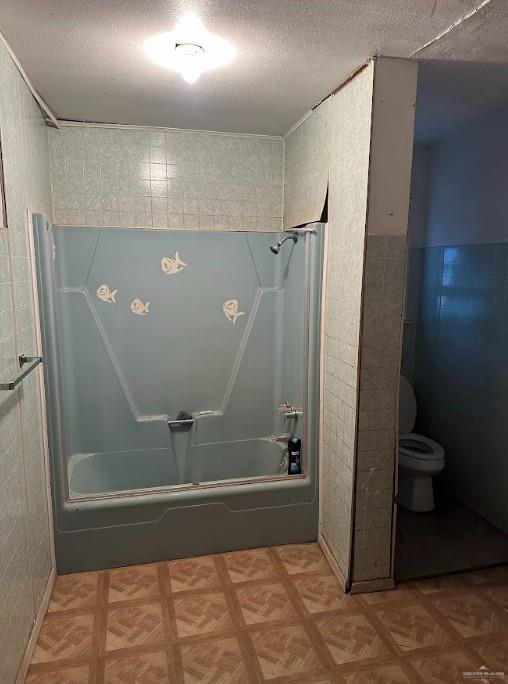 bathroom with toilet, tub / shower combination, and a textured ceiling