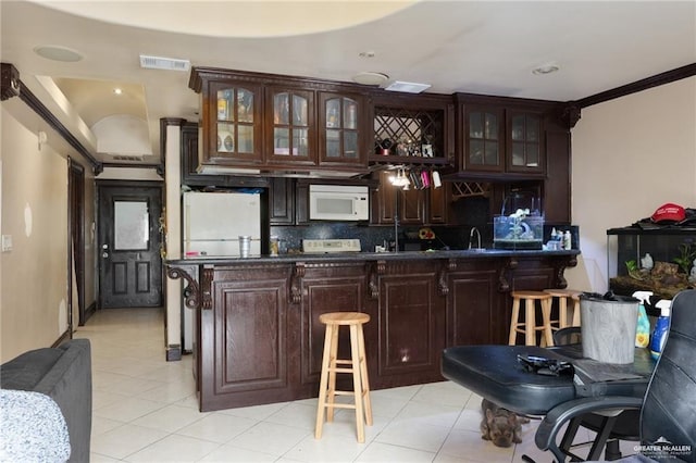 bar featuring dark brown cabinets, white appliances, crown molding, and backsplash