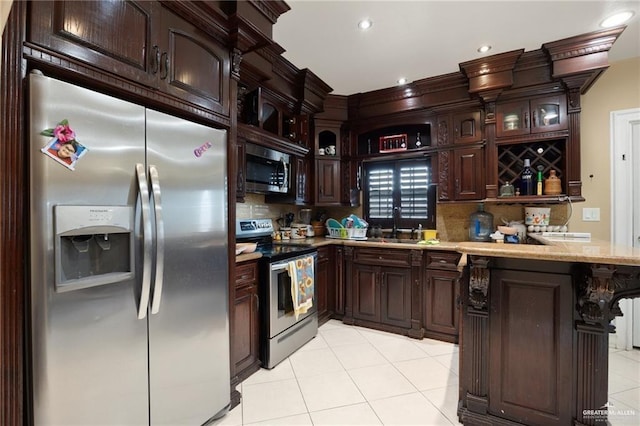 kitchen with kitchen peninsula, dark brown cabinets, stainless steel appliances, sink, and light tile patterned flooring