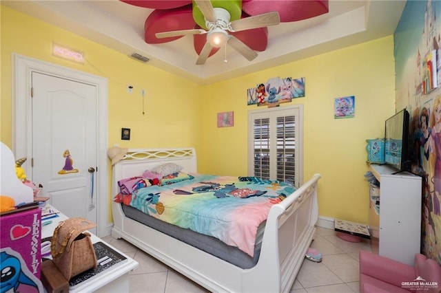 tiled bedroom featuring a tray ceiling and ceiling fan