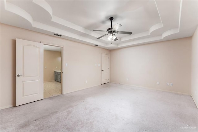 carpeted spare room featuring ceiling fan and a tray ceiling