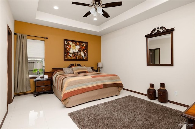 tiled bedroom with a tray ceiling and ceiling fan