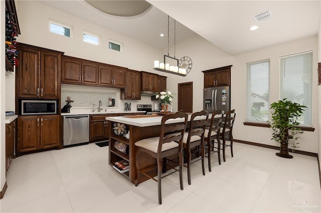 kitchen with dark brown cabinetry, a kitchen island, a healthy amount of sunlight, and appliances with stainless steel finishes