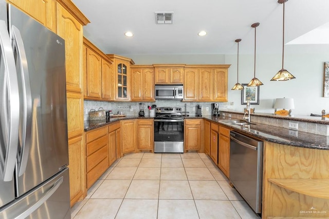 kitchen with dark stone countertops, sink, hanging light fixtures, and appliances with stainless steel finishes