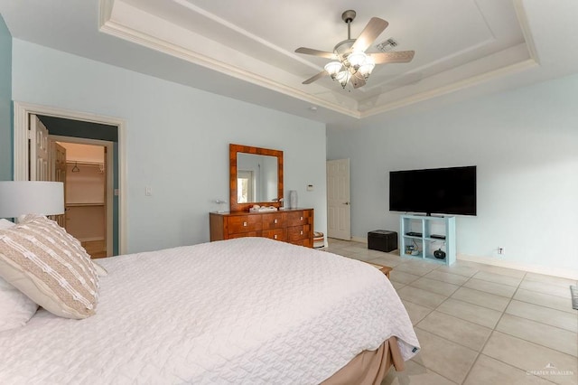 tiled bedroom featuring a raised ceiling, a closet, a spacious closet, and ceiling fan